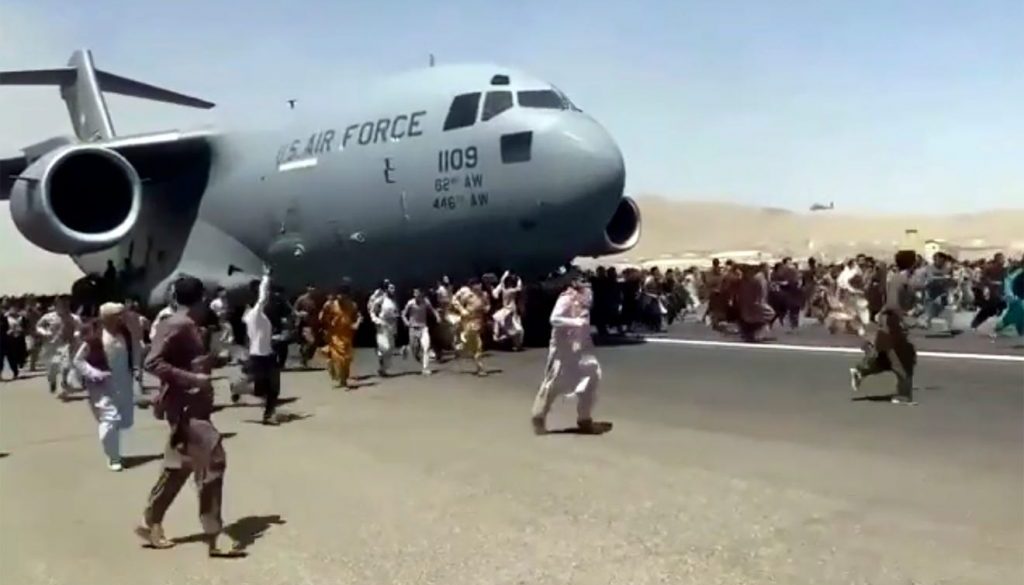 Hundreds of people run alongside a U.S. Air Force C-17 transport plane as it moves down a runway of the international airport, in Kabul, Afghanistan, Monday, Aug.16. 2021. Thousands of Afghans have rushed onto the tarmac at the airport, some so desperate to escape the Taliban capture of their country that they held onto the American military jet as it took off and plunged to death.