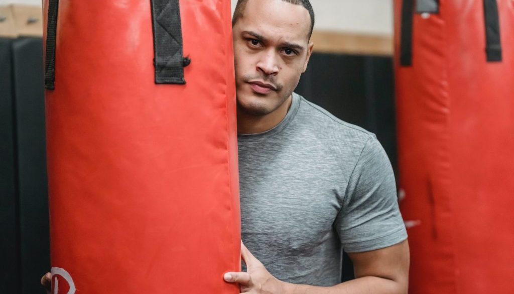 ethnic boxer between heavy bags in gym